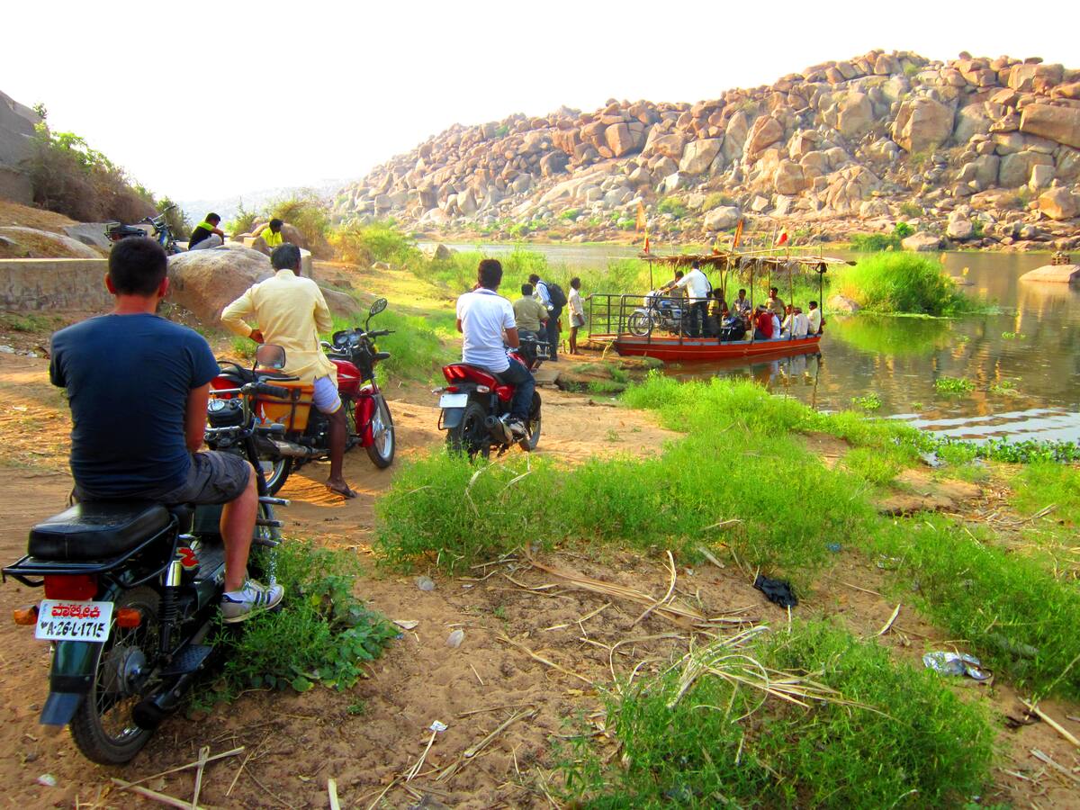 Voyageurs et scooters attendant le coracle sur la rive de la Tungabhadra
